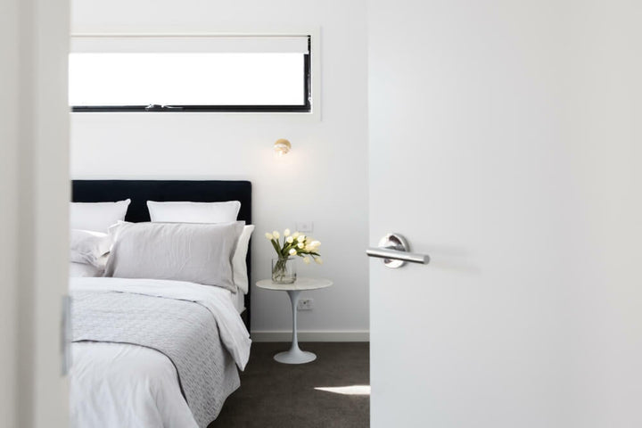 White roller blinds on white wall in bedroom