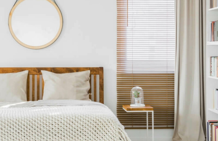 Wooden venetian blind with beige curtain in bedroom