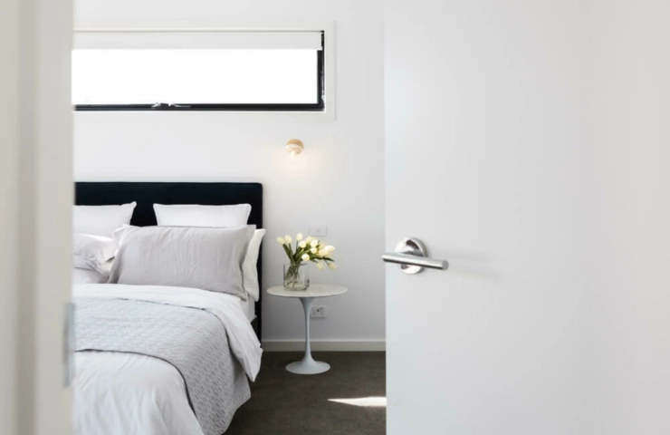 White roller blinds on white wall in bedroom