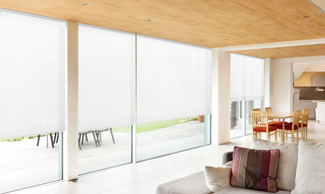 Honeycomb Light filter blinds in sunny living space with large windows and sliding doors