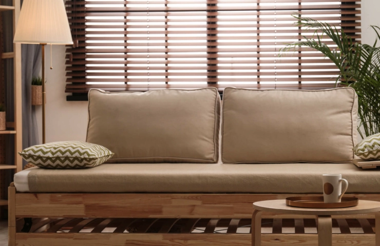 Wooden blinds in living room with beige couch