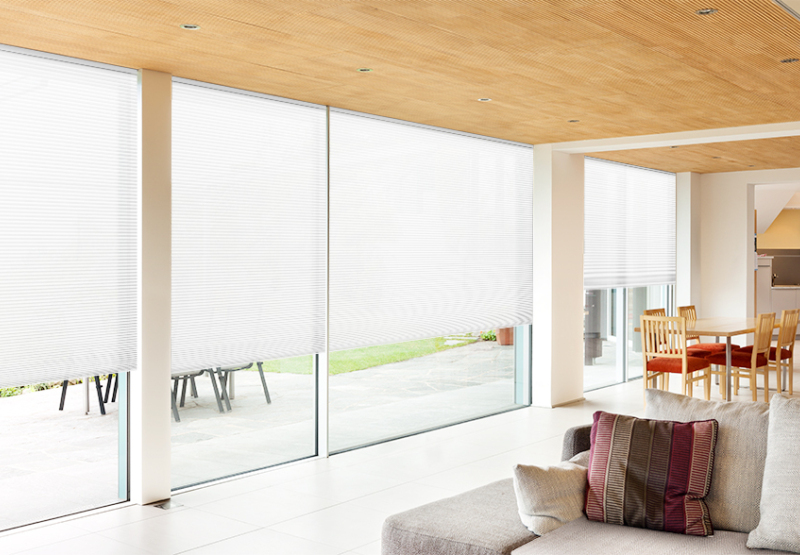 Honeycomb Light filter blinds in sunny living space with large windows and sliding doors